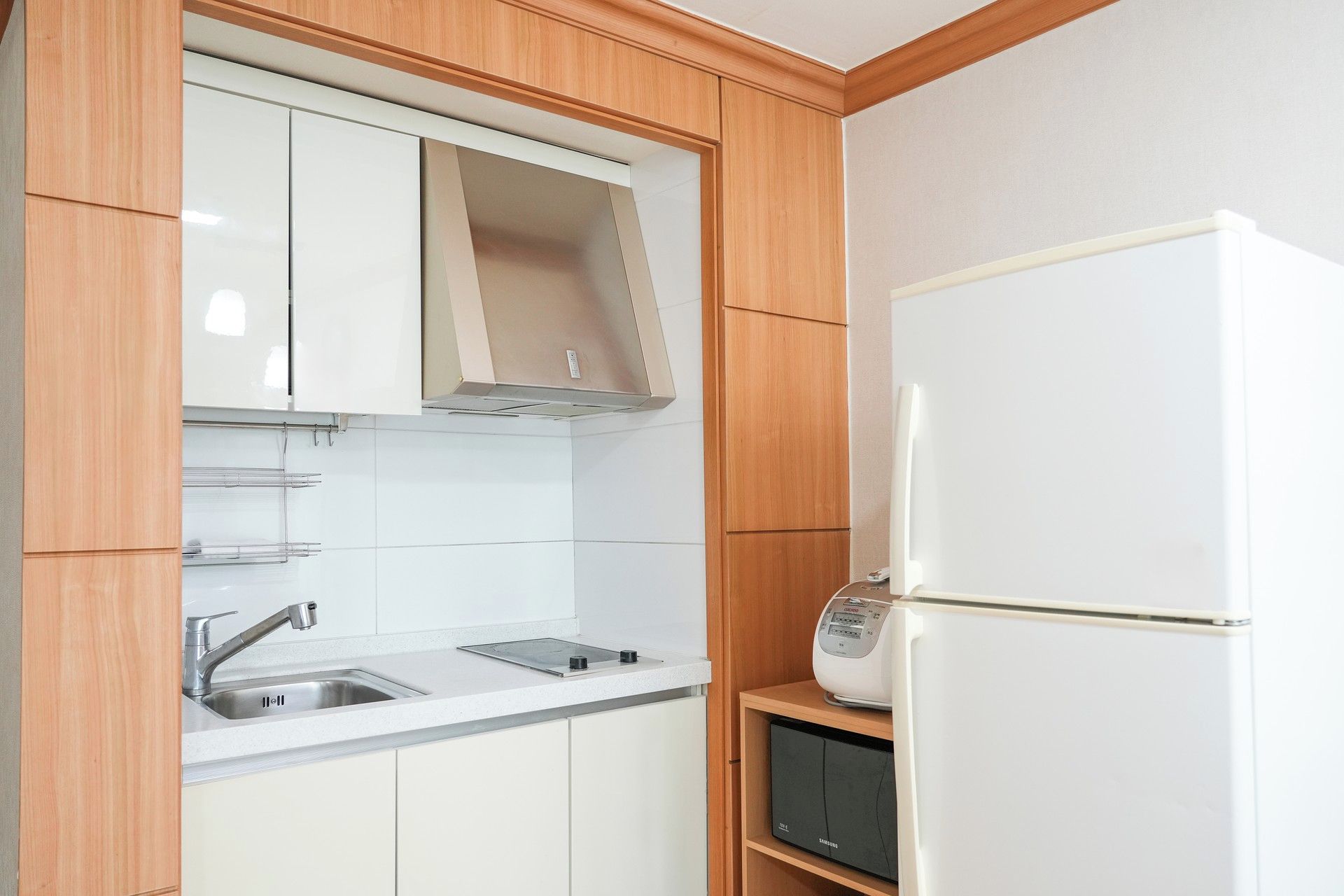 A kitchen with a built-in microwave, a stainless steel sink, and wooden cabinets.