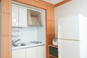 Una cocina con microondas integrado, un lavamanos de acero inoxidable y armarios de madera.