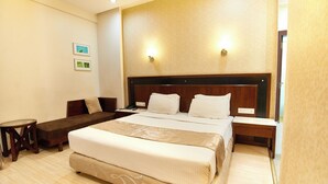 A hotel room with a large bed, a bedside table, a chair, and a small table. - Hotel Sai Mahal (Rahata)