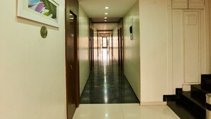 A hotel corridor with a framed picture on the left, a phone on the wall, and a staircase on the right. - Hotel Sai Mahal (Rahata)