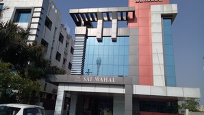 The exterior of Hotel Sai Mahal with a modern architectural design, featuring a prominent entrance and a clear sky above. - Hotel Sai Mahal (Rahata)