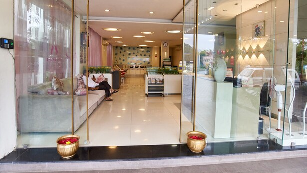 A modern hotel lobby with a reception desk, seating area, and a glass partition. - Hotel Sai Mahal (Rahata)