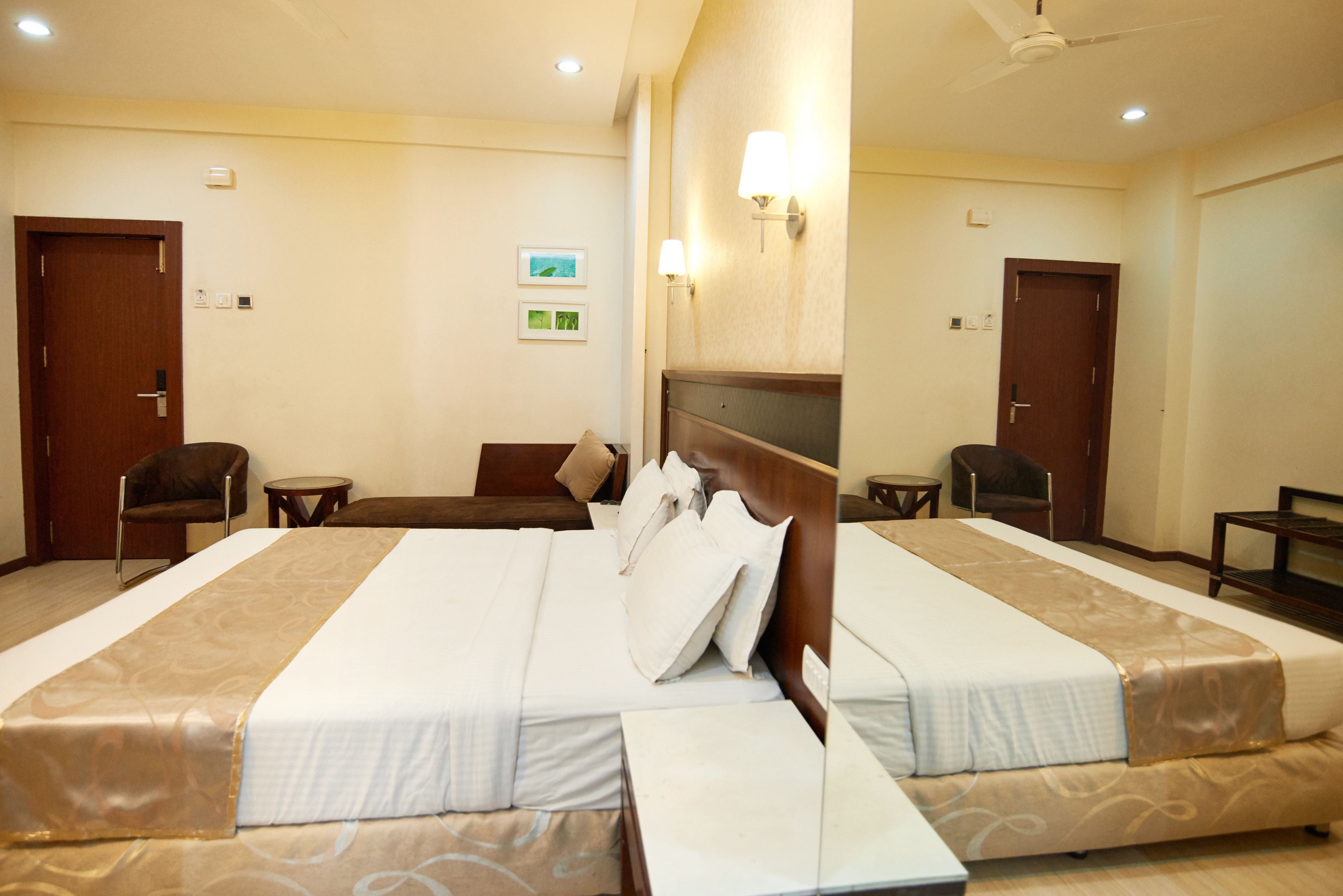 Habitación de hotel con dos camas, un área de descanso y una mesita.