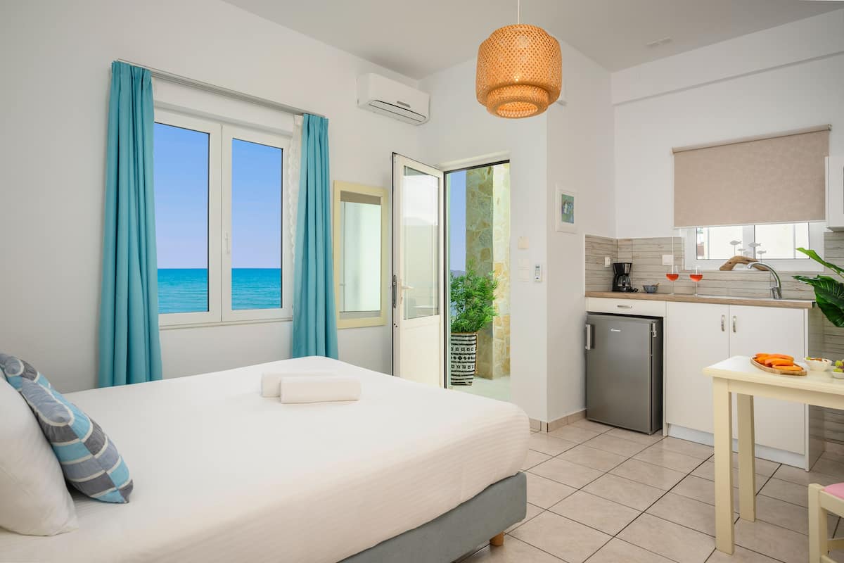 A bedroom with a bed, a small desk, and a view of the sea.