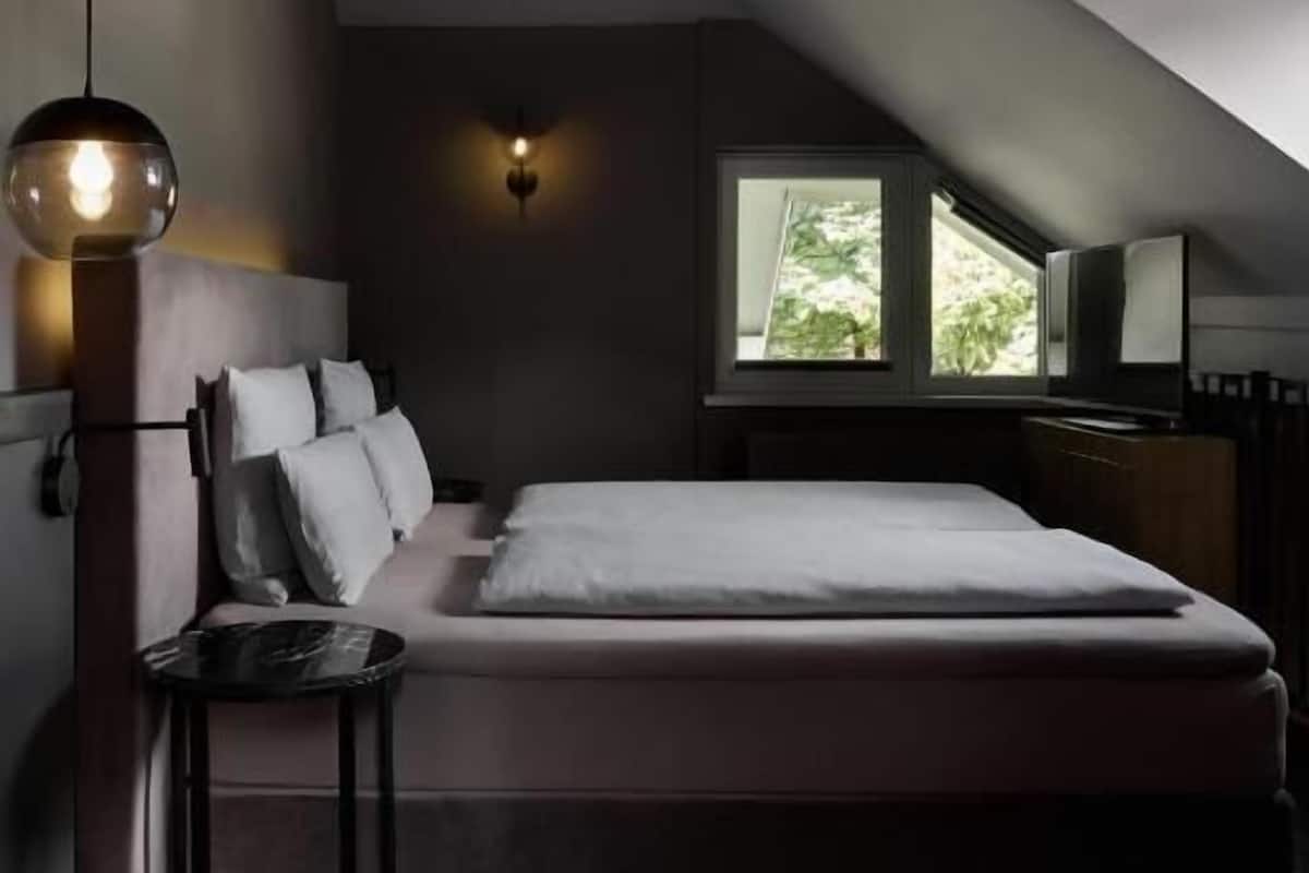 Un dormitorio moderno con una cama grande, un escritorio y un ventanal con vistas a zonas verdes.
