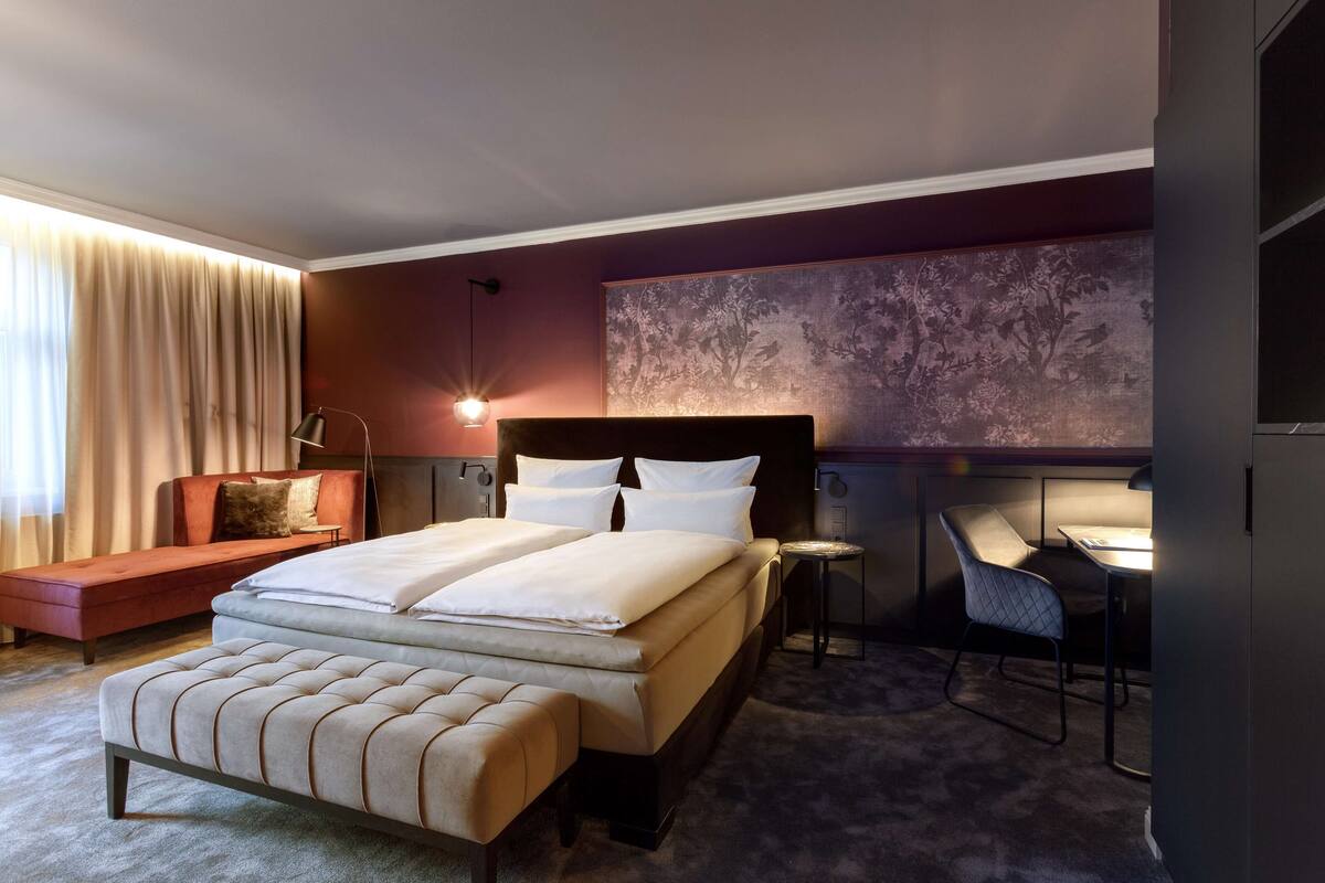 Una habitación de hotel moderna con una cama grande, un sofá, un escritorio y una silla.