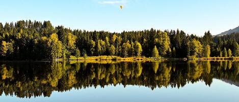 A calm lake with a clear reflection of trees and a sky with clouds.