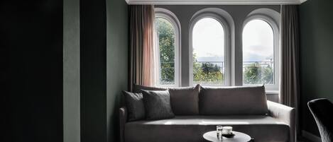 A modern room with a grey sofa, a small round table, and a window with curtains.