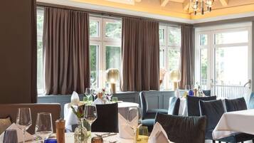 A dining area with round tables, chairs, and hanging light fixtures.