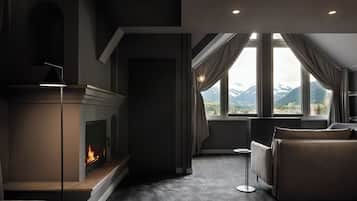 A modern living room with a fireplace, a sofa, and a view of mountains through large windows.