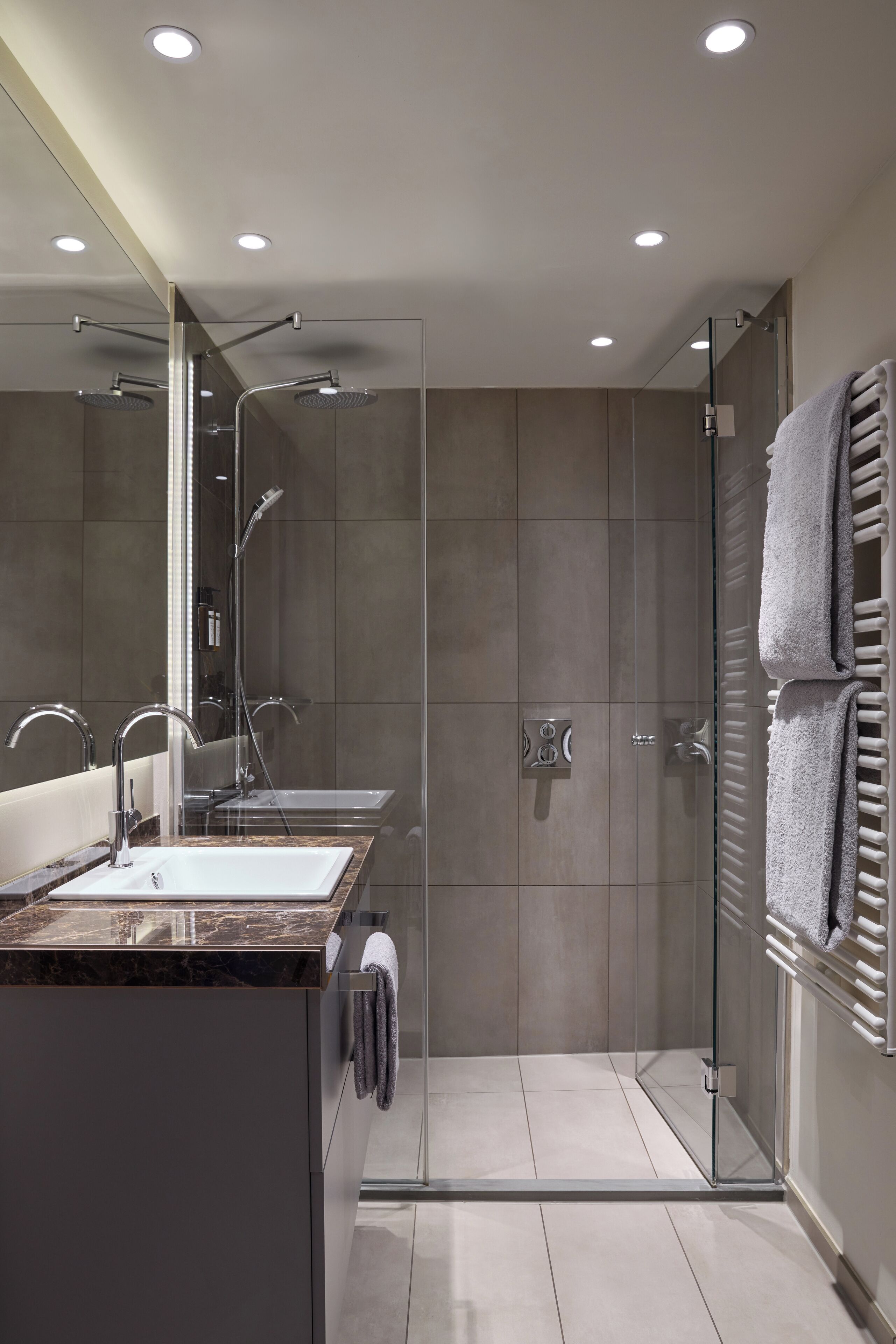 Une salle de bain moderne avec une douche à parois de verre, un meuble-lavabo et un porte-serviettes.