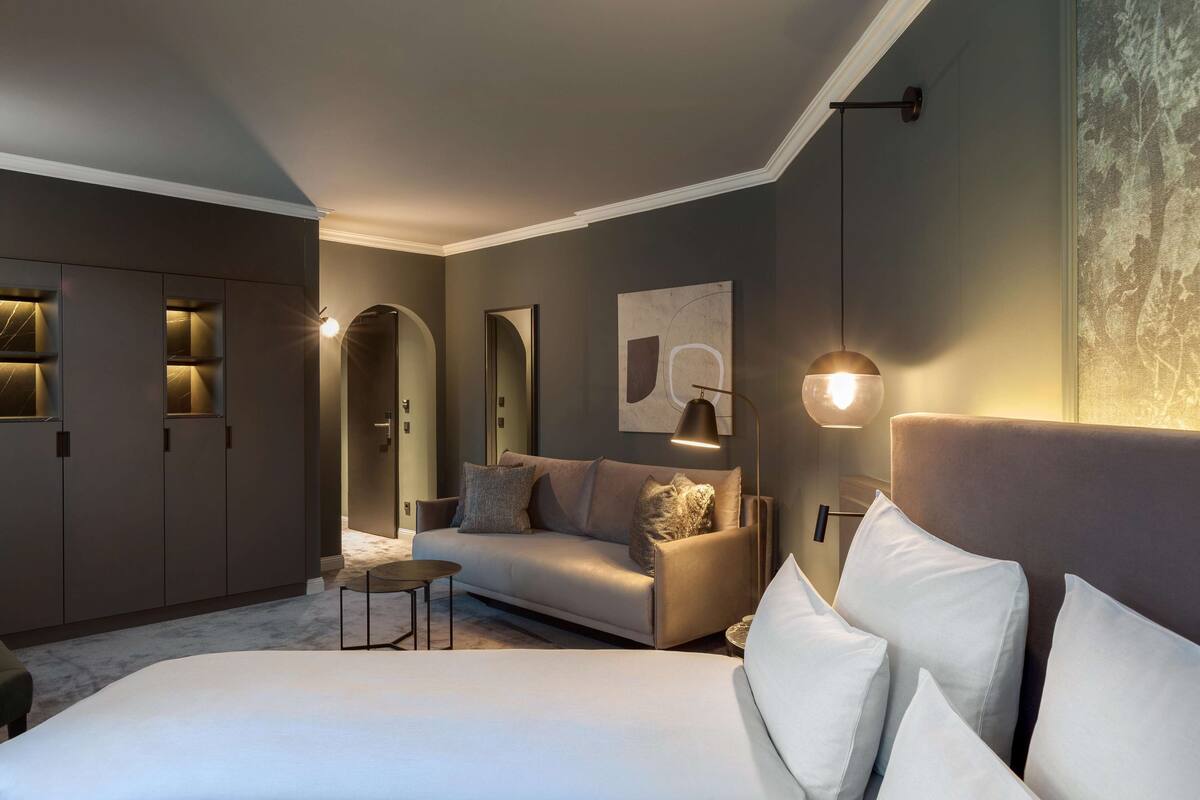 Una habitación de hotel moderna con una cama grande, un sofá, un escritorio y un armario.