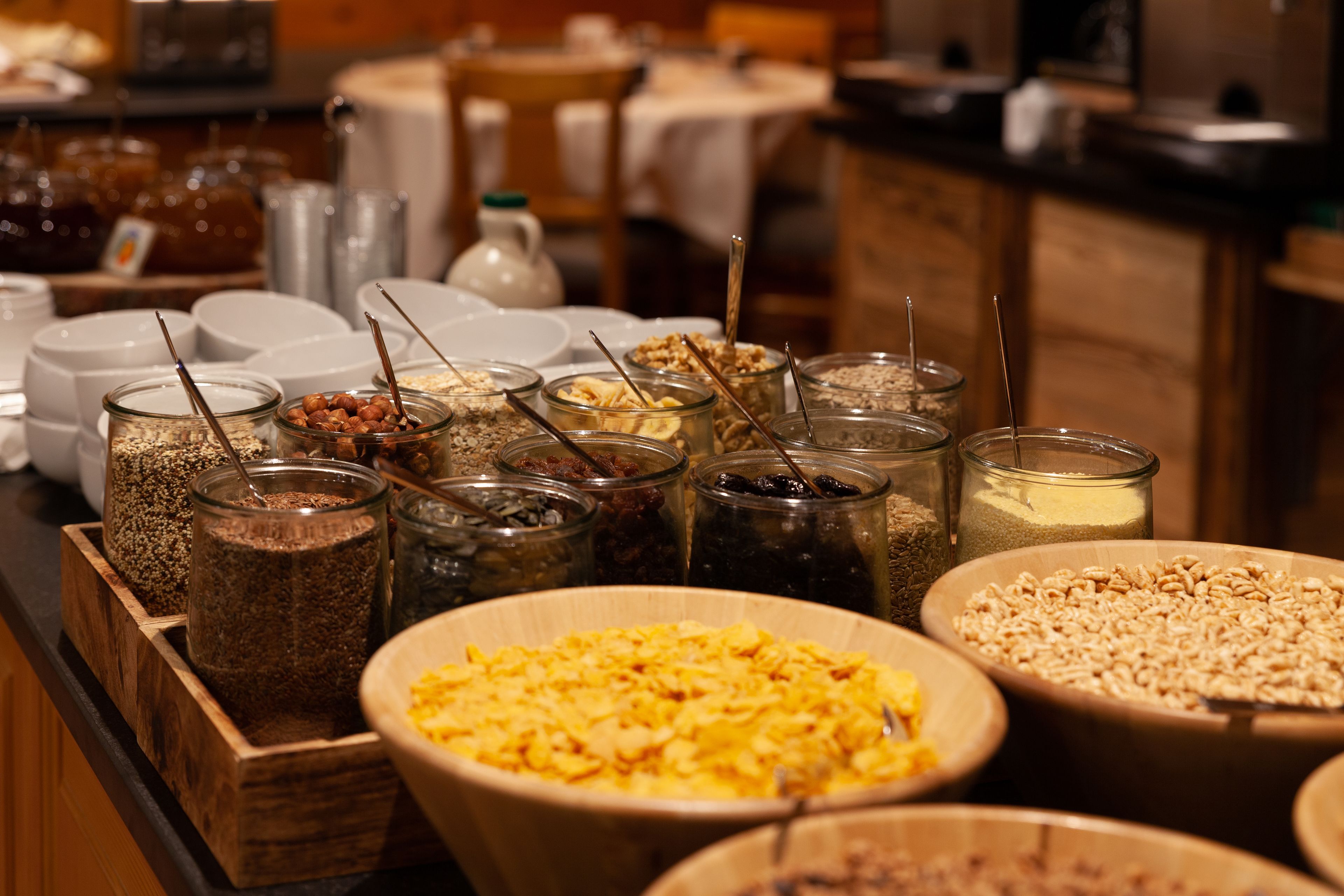 A buffet with various food items and containers, including bowls and jars of cereals and spreads.