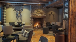 A cozy living room with a stone fireplace, comfortable seating, and a deer skull mounted on the wall.