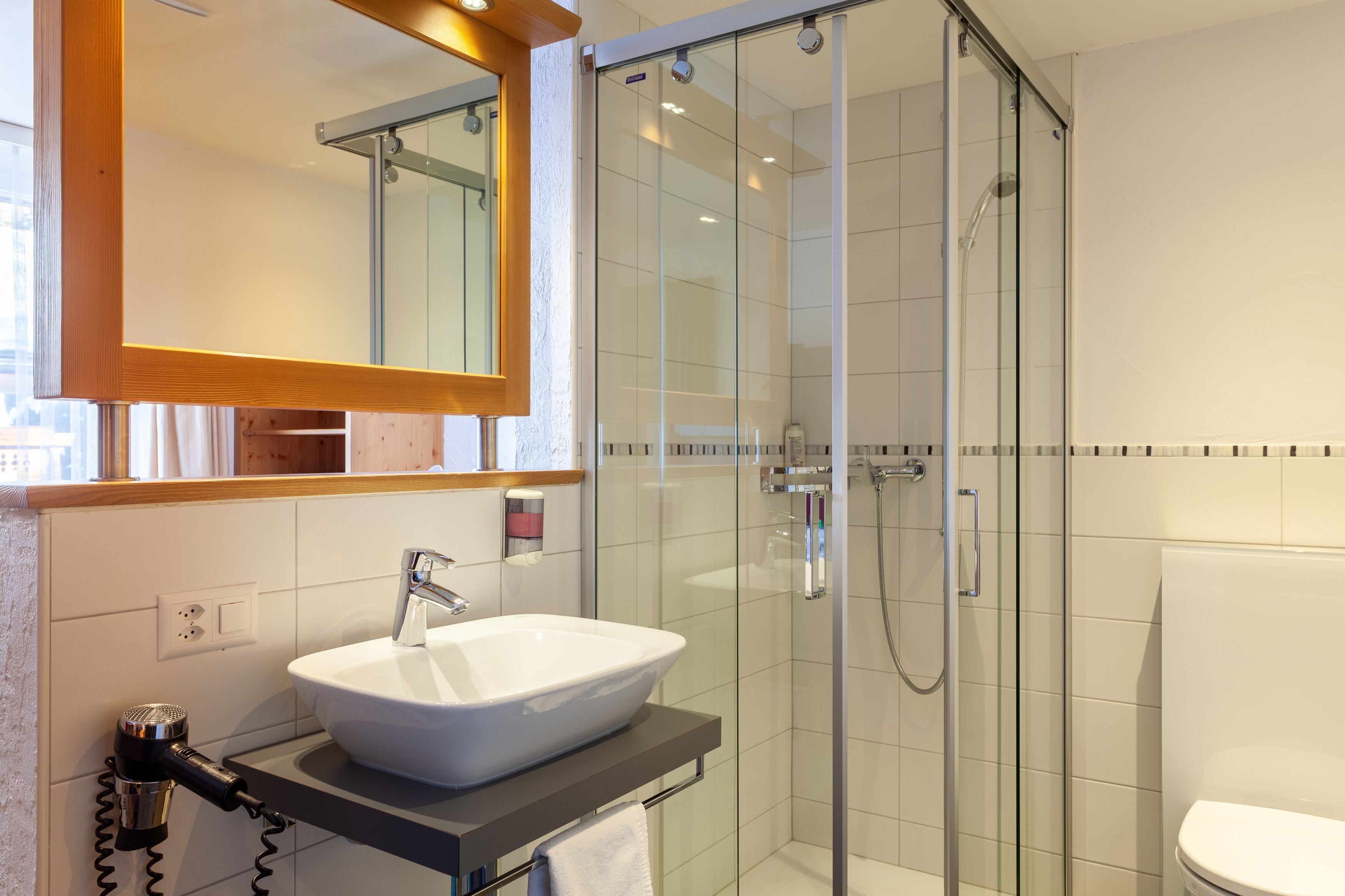 A modern bathroom with a glass-enclosed shower, a white sink, and a mirror above the sink.