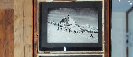 A wooden-framed photo display with three black and white photographs of mountainous landscapes and a group of people.