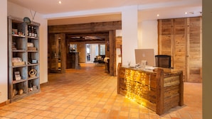 A spacious room with a wooden reception desk, a tiled floor, and a rustic wooden wall.