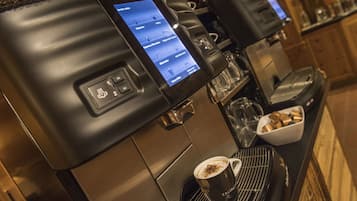 A coffee machine with a digital display menu, a cup of coffee, and a coffee grinder.