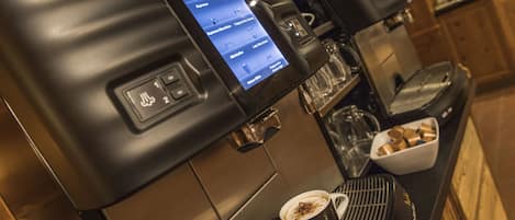 A coffee machine with a digital display menu, a cup of coffee, and a coffee grinder.