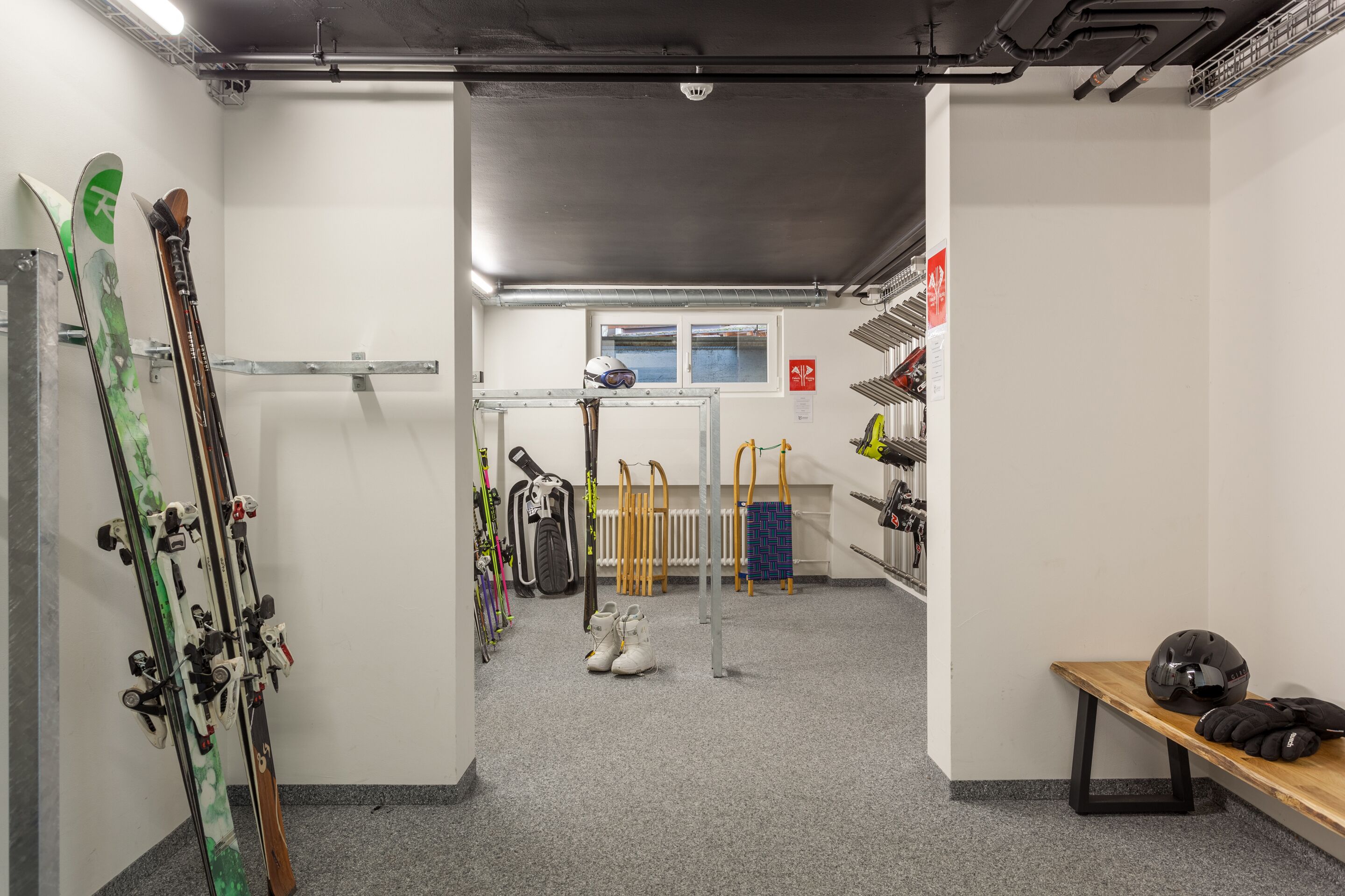 A ski storage room with skis, ski boots, and helmets.