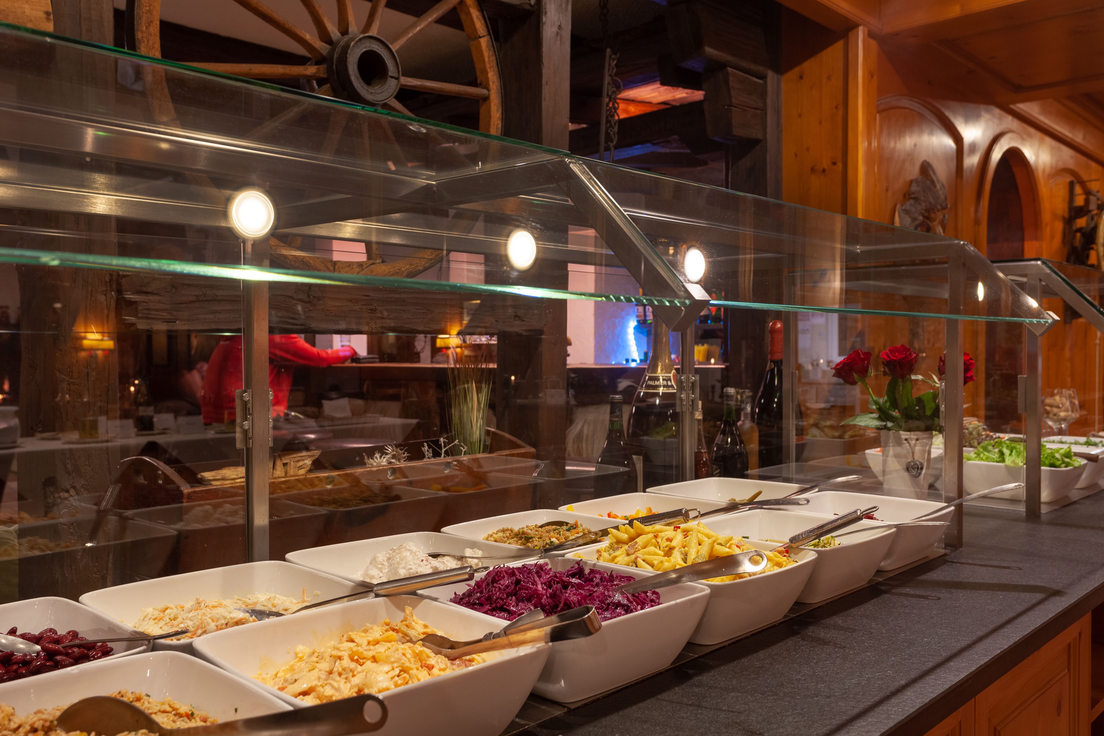 A buffet with various food items in white bowls, a glass display case, and wooden interior decor.