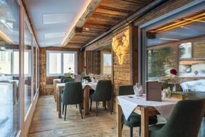 A restaurant with wooden interiors, tables set for dining, and a neon deer sign on the wall.