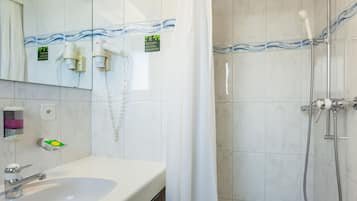 Un bagno con lavandino, specchio, porta asciugamani e doccia con tenda.