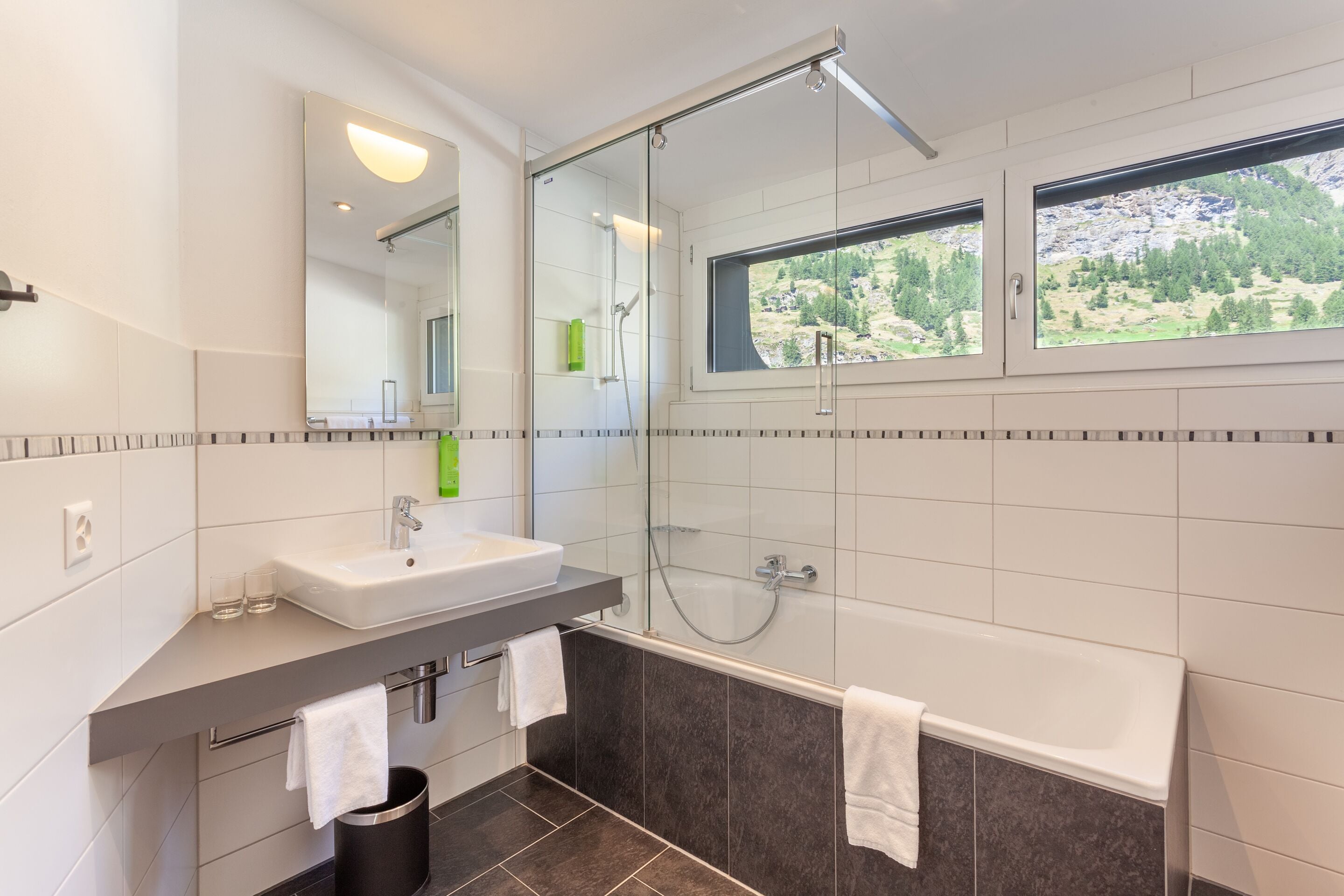 A modern bathroom with a glass-enclosed shower, a bathtub, and a sink with a mirror above.