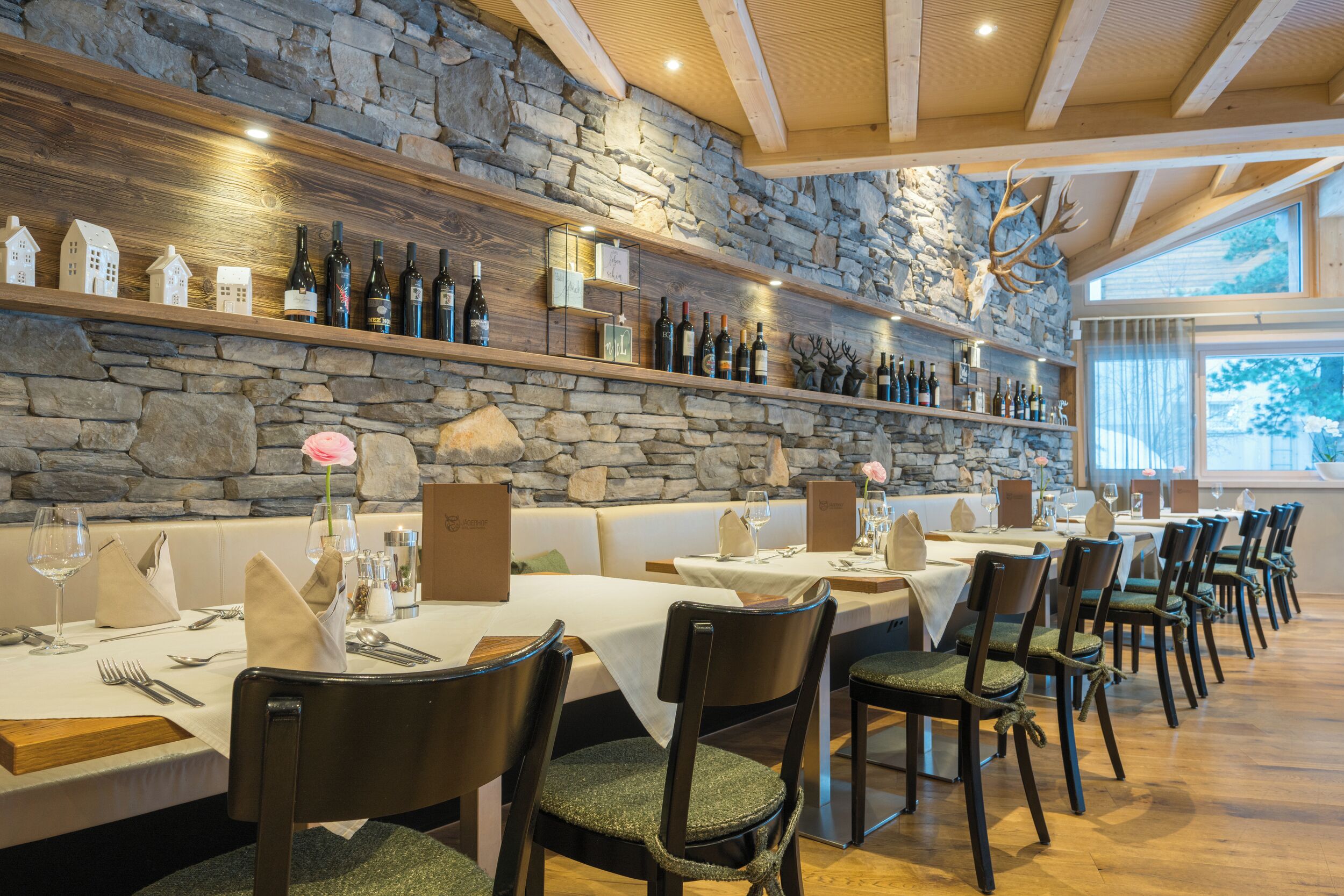 Restaurante com paredes de pedra, vigas de madeira e uma longa mesa de jantar com cadeiras.