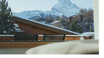 A mountain view with a snow-covered peak, wooden buildings, and a wooden roof.