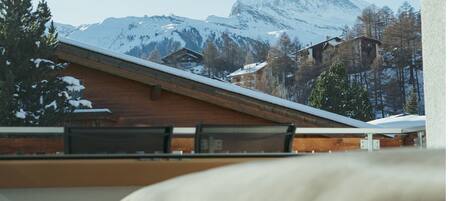 A mountain view with a snow-covered peak, wooden buildings, and a wooden roof.