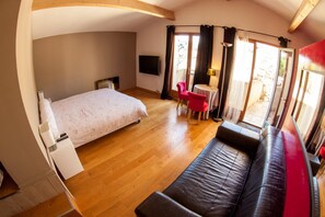 A bedroom with a bed, a sofa, a TV, a small table, and a chair. - Les Terrasses de Castelnau (Castelnau-le-Lez)