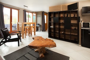 Una sala de estar moderna con una gran mesa de centro de madera, un comedor con una mesa y sillas de madera, y un mueble empotrado con televisión y estanterías.