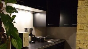 A modern kitchen with dark cabinets, a built-in oven, and a coffee maker. - Les Terrasses de Castelnau (Castelnau-le-Lez)
