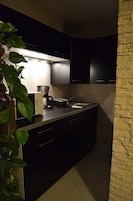Una cocina moderna con armarios oscuros, horno empotrado y cafetera.