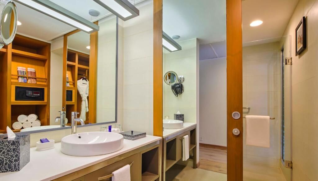 A modern bathroom with a large mirror, a round sink, and a towel rack.