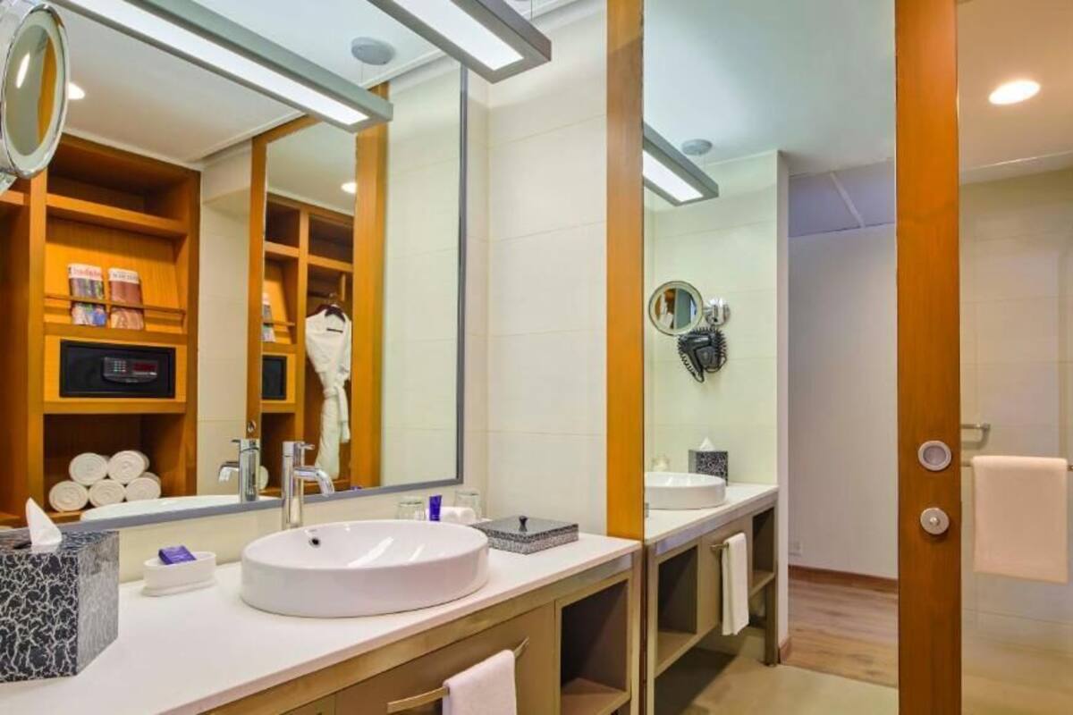 Ein modernes Badezimmer mit einem großen Spiegel, einem runden Waschbecken und einem Handtuchhalter.