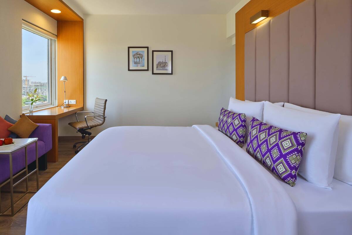 Ein Hotelzimmer mit einem großen Bett, einem Schreibtisch, einem Stuhl und zwei gerahmten Bildern an der Wand.