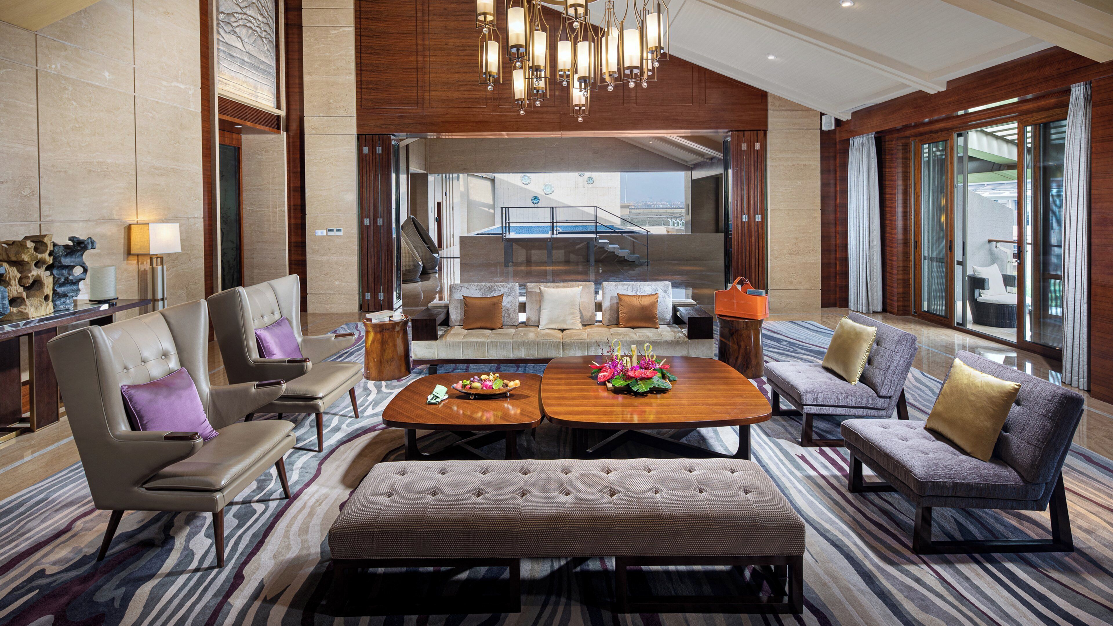 A spacious lobby with a central seating area, a view of the outdoors, and a modern chandelier.