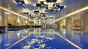 A spacious indoor swimming pool with a clear view of the ceiling and walls, featuring a modern design with geometric light fixtures and a central seating area. - InterContinental Kunming by IHG (Kunming)
