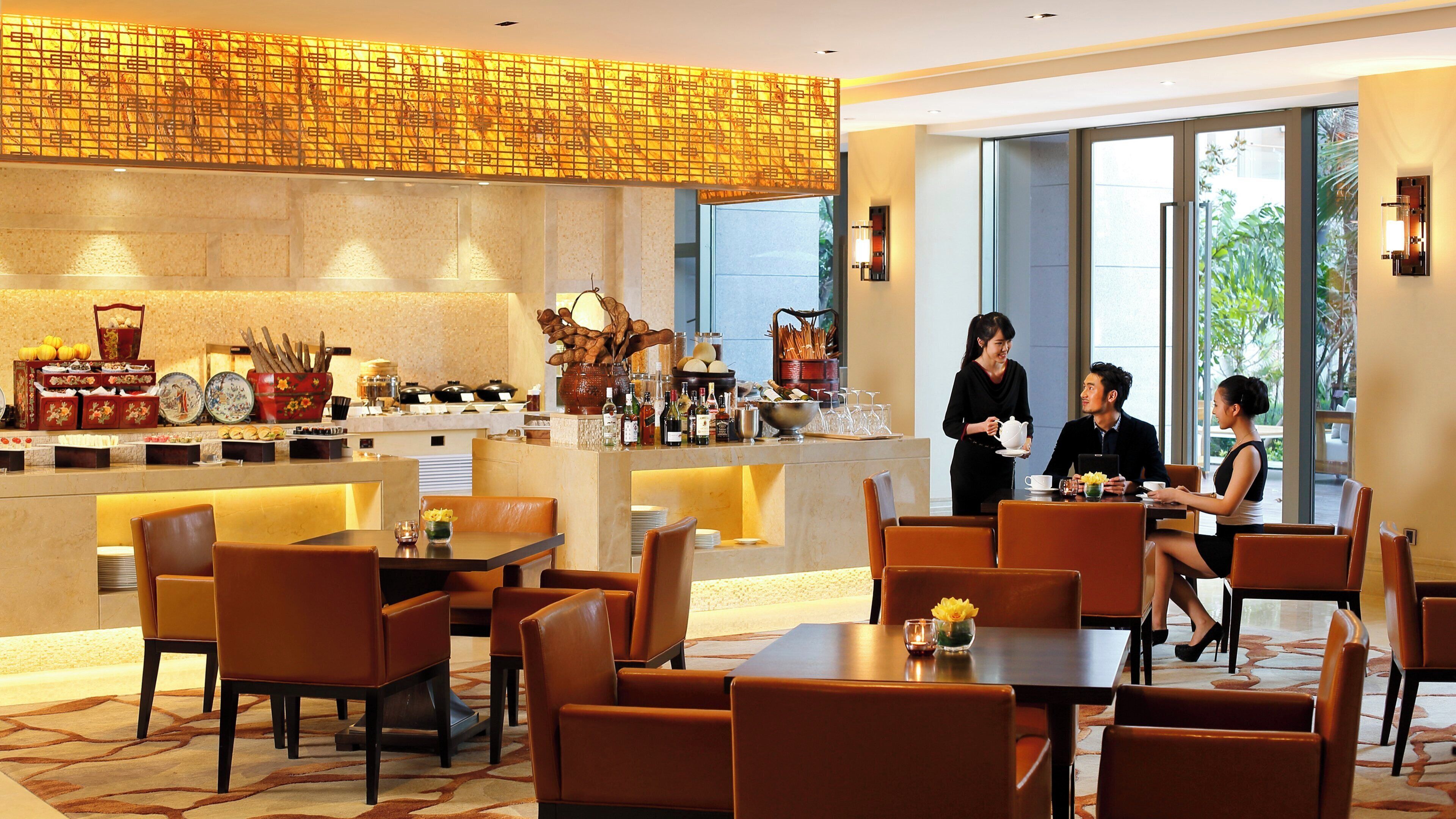 A hotel lobby with a bar area, seating arrangements, and a view of the outdoors.