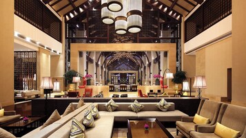 A spacious lobby with a high ceiling, a central seating area, and a reception desk.