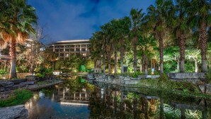 A serene hotel courtyard with a reflective pond, palm trees, and a building with multiple floors and balconies. - InterContinental Kunming by IHG (Kunming)