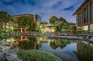 A serene garden with a gazebo, reflecting buildings, and a calm pond.