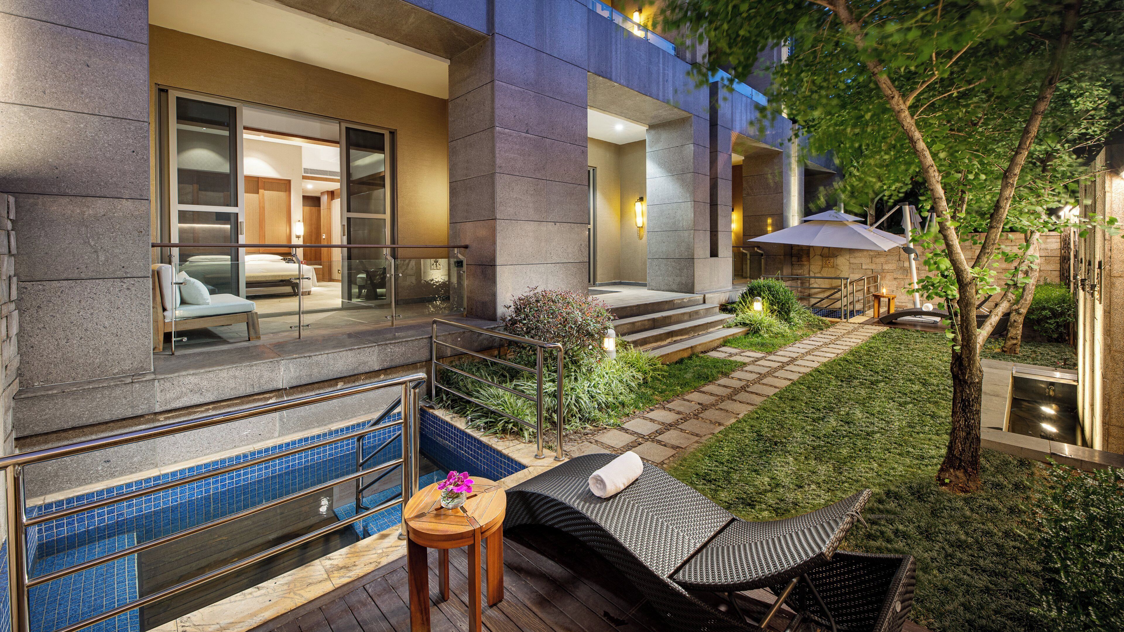 A modern outdoor area with a pool, lounge chairs, and a well-maintained garden.