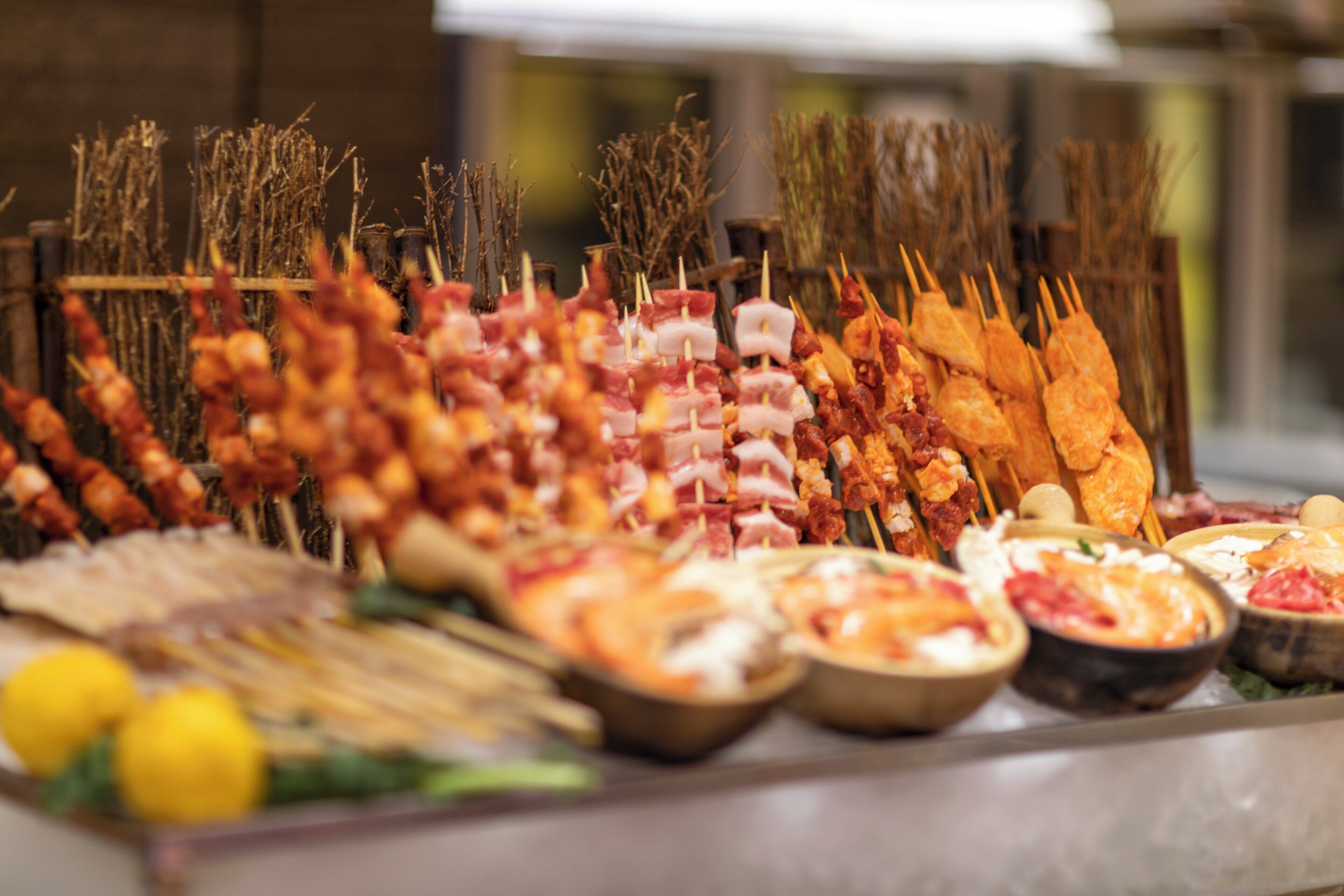 A variety of skewered meats and dips on a tray.