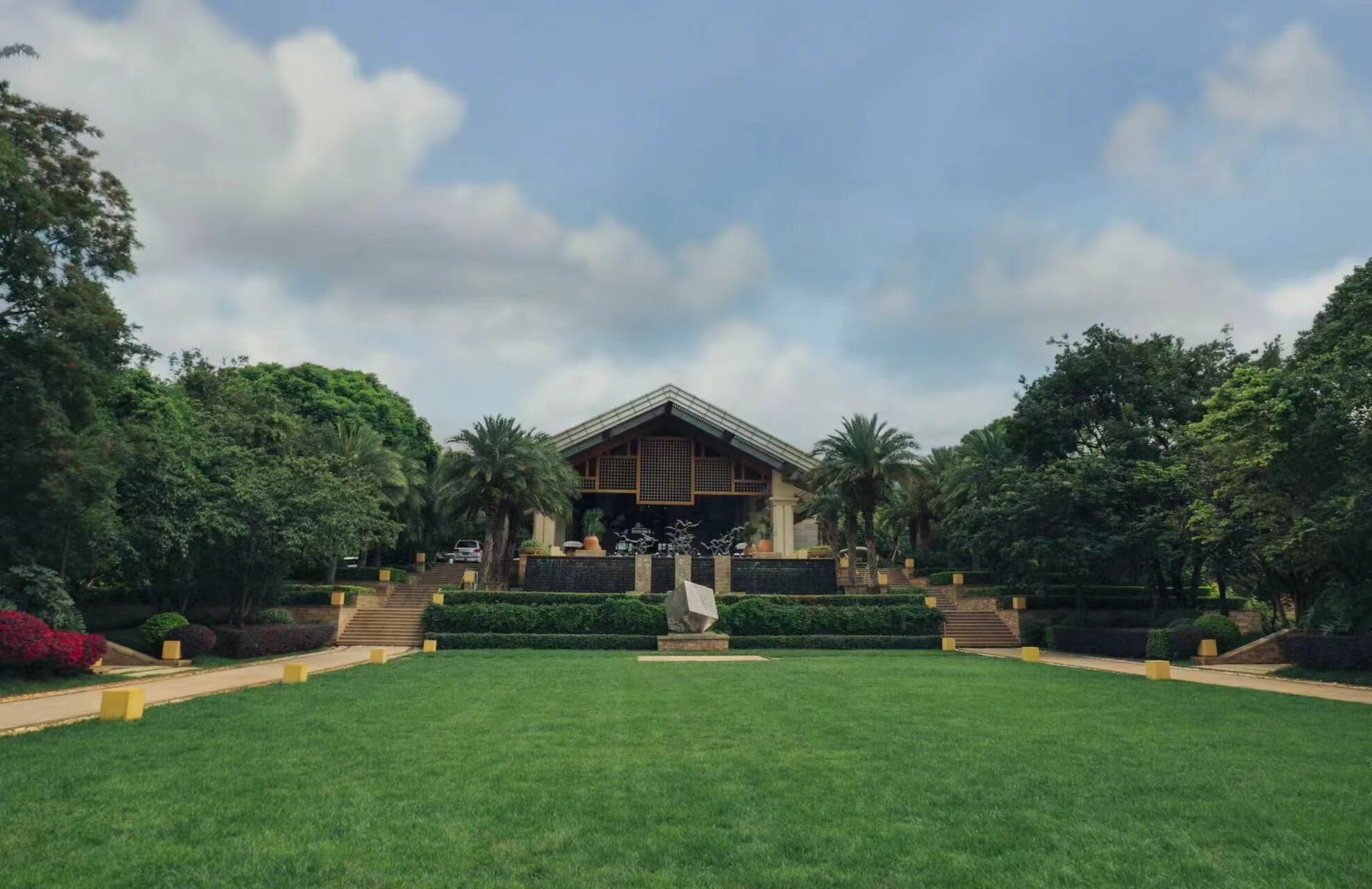 A traditional building with a symmetrical facade, surrounded by a well-manicured lawn and various trees.