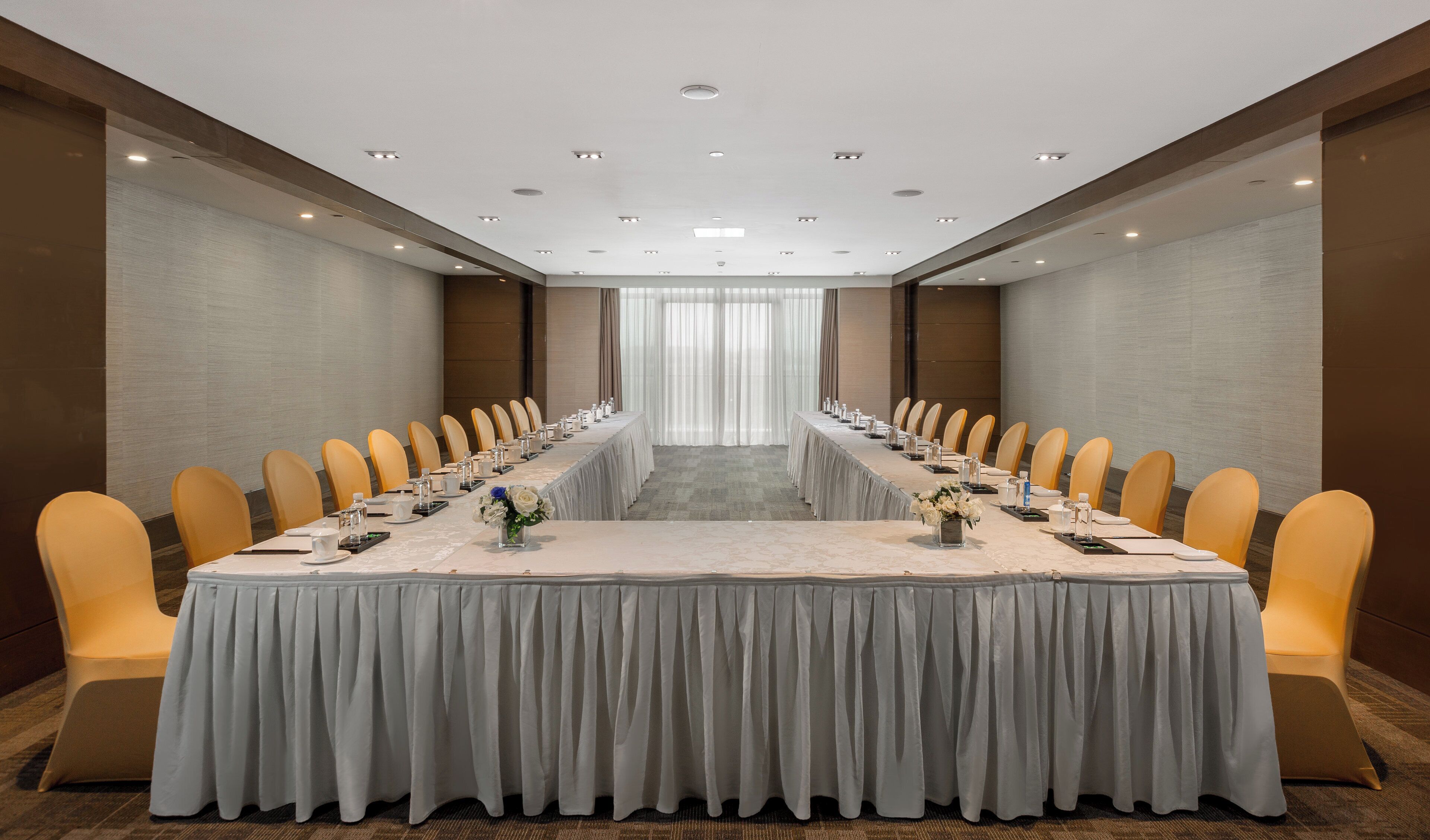 Un salón de conferencias con una larga mesa, sillas y una decoración en colores neutros.