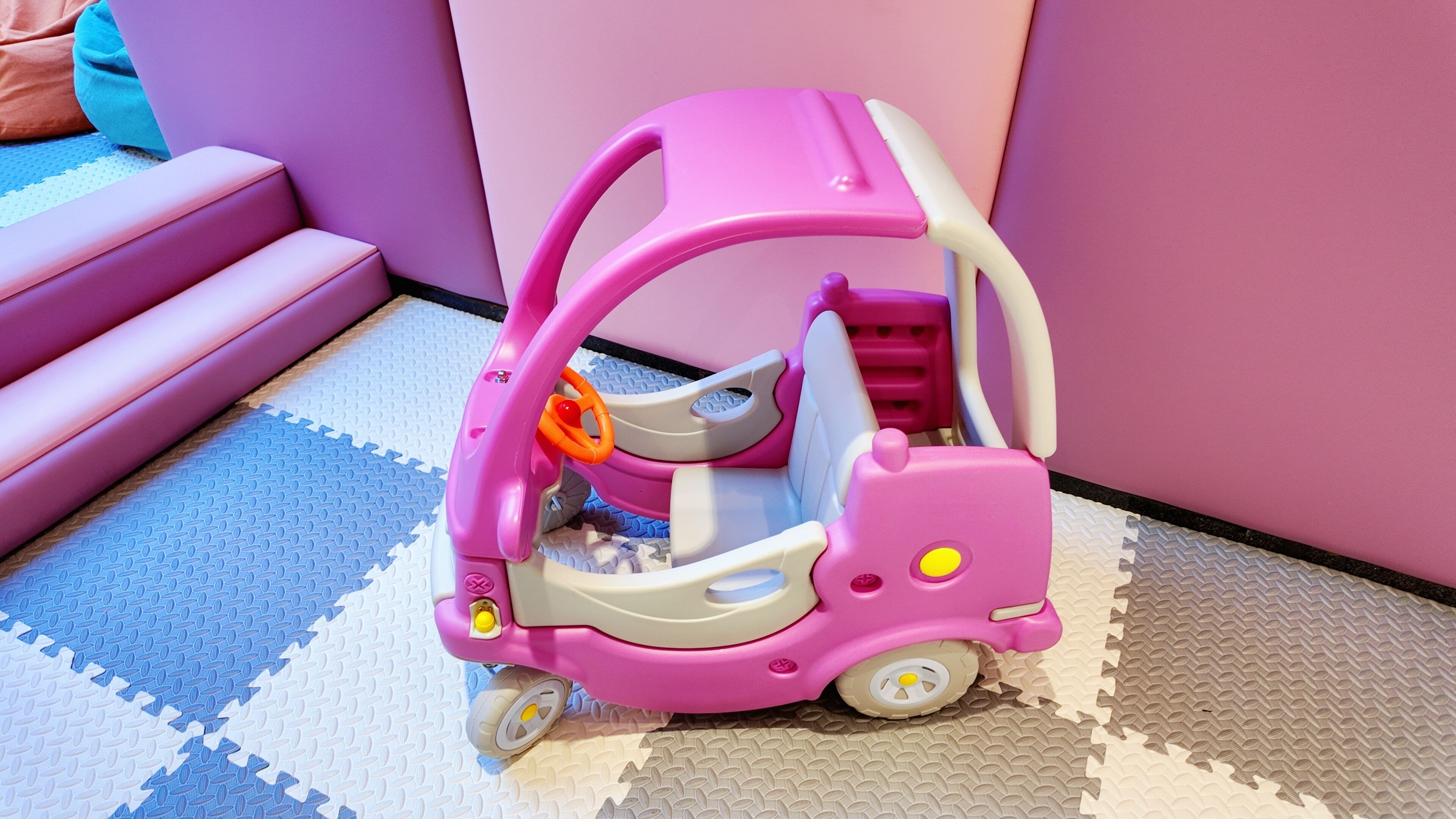 A pink toy car on a patterned floor.