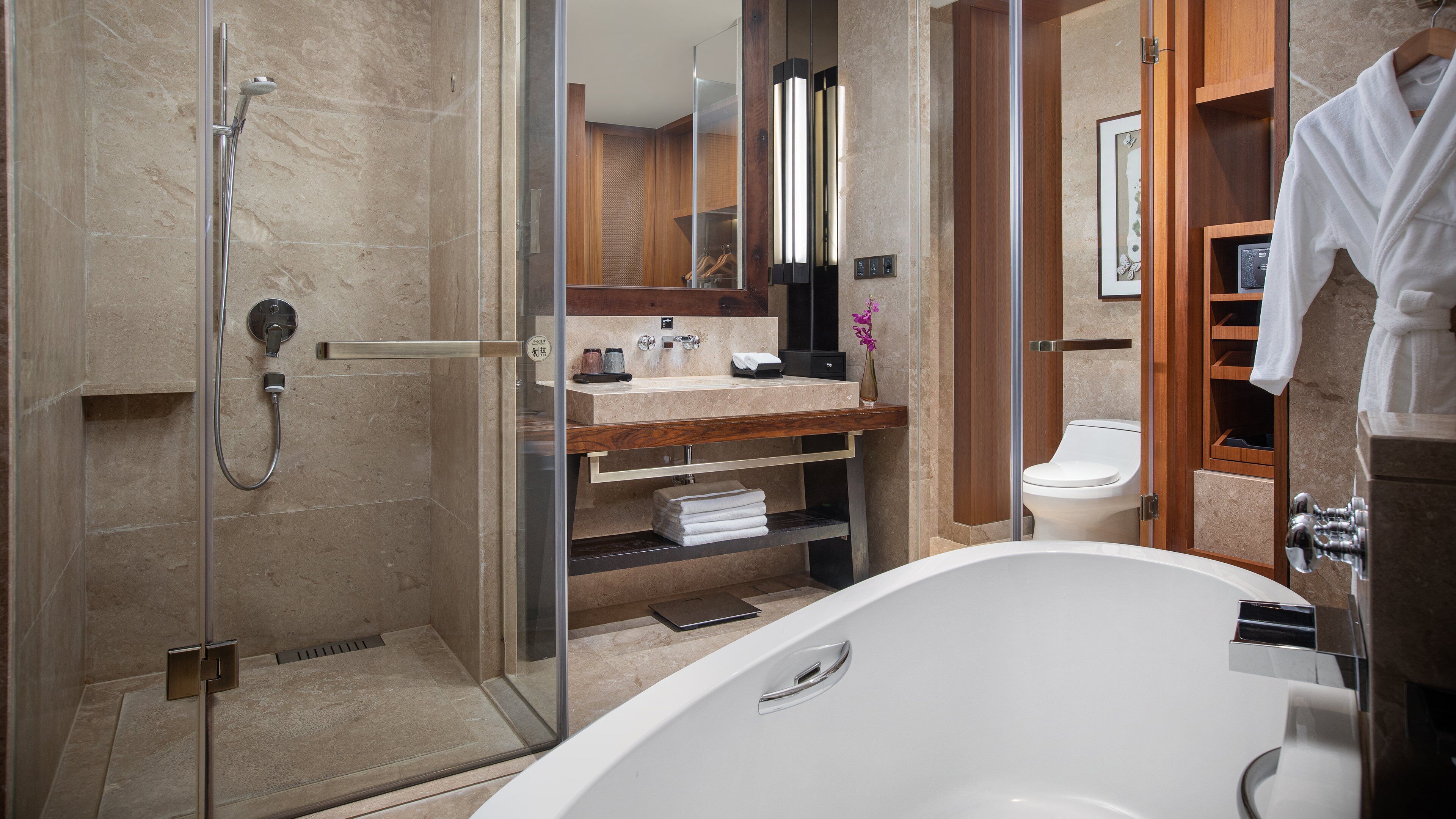 A modern bathroom with a glass-enclosed shower, a freestanding bathtub, and a vanity with a mirror and towel rack.